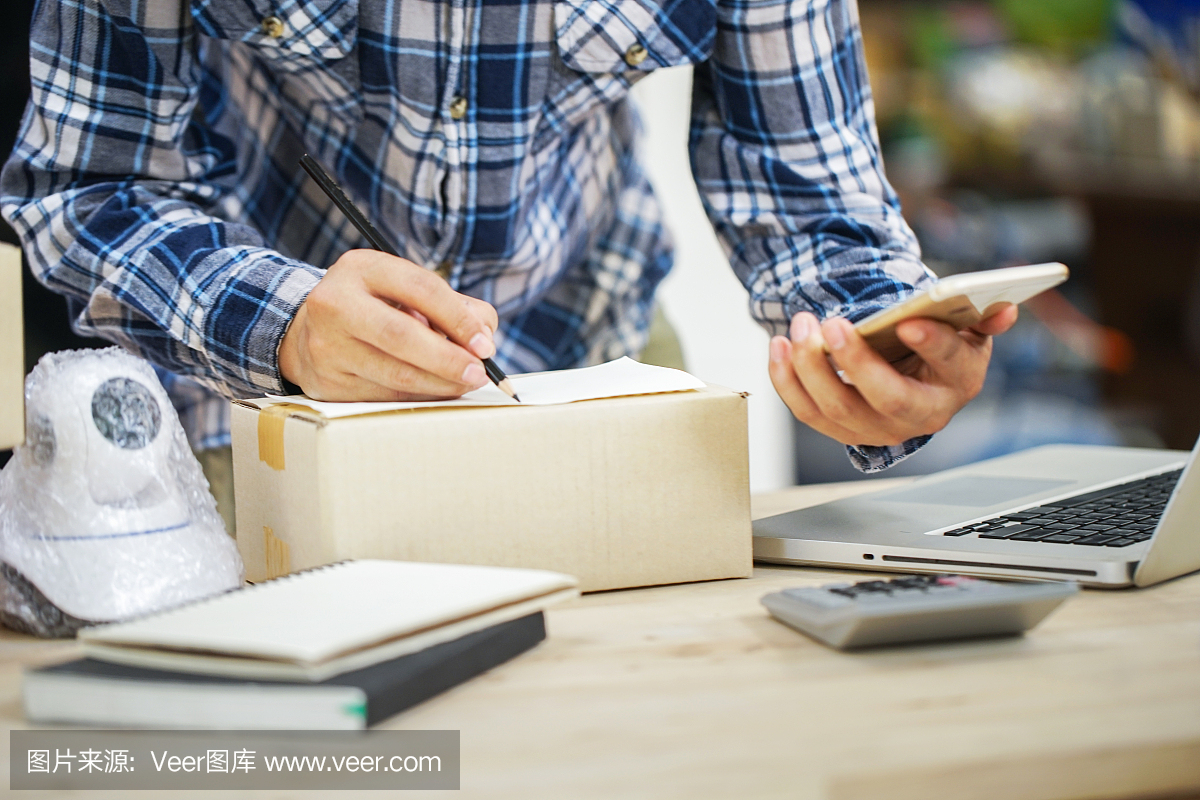 年輕的創(chuàng)業(yè)小企業(yè)主在工作場所的盒子里裝攝像頭閉路電視。自由職業(yè)者銷售者準(zhǔn)備產(chǎn)品的包裝過程在家里。網(wǎng)絡(luò)銷售,網(wǎng)絡(luò)營銷,